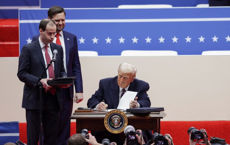 Reuters/Mike Segar/Proibida reprodução U.S. President Donald Trump signs executive orders as U.S. Vice President J.D. Vance looks on during a rally on the inauguration day of his second Presidential term, inside Capital One, in Washington, U.S. January 20, 2025. Reuters/Mike Segar/Proibida reprodução