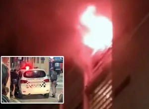 O apartamento que ficou todo queimado está interditado. No detalhe a mulher sendo conduzida pela PM - Foto: Reprodução/TV