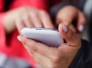 two-beautiful-students-using-mobile-phone-street_0.jpg